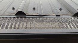 Gutter guard installed at the edge of a metal roof