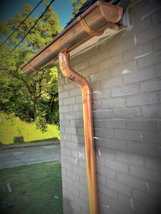 Copper half-round gutter with a round copper downspout at a roof corner