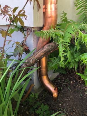 Round metal downspout routed down an exterior wall