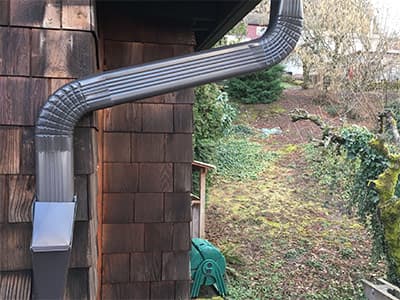 Downspout cleanout cover installed for easy maintenance access